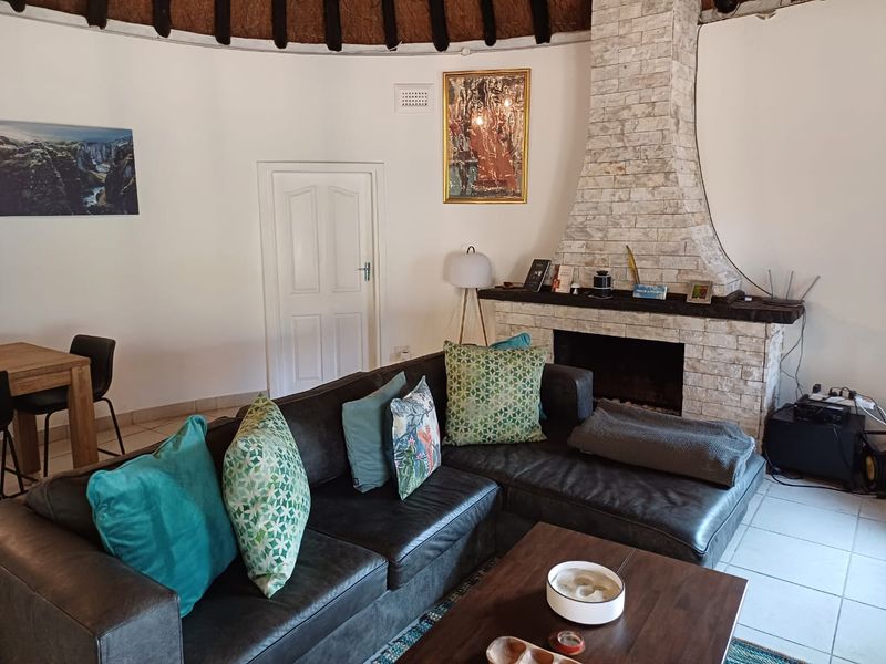 A cozy living room featuring a prominent stone-clad fireplace and a unique thatched roof ceiling, creating a rustic and inviting atmosphere.