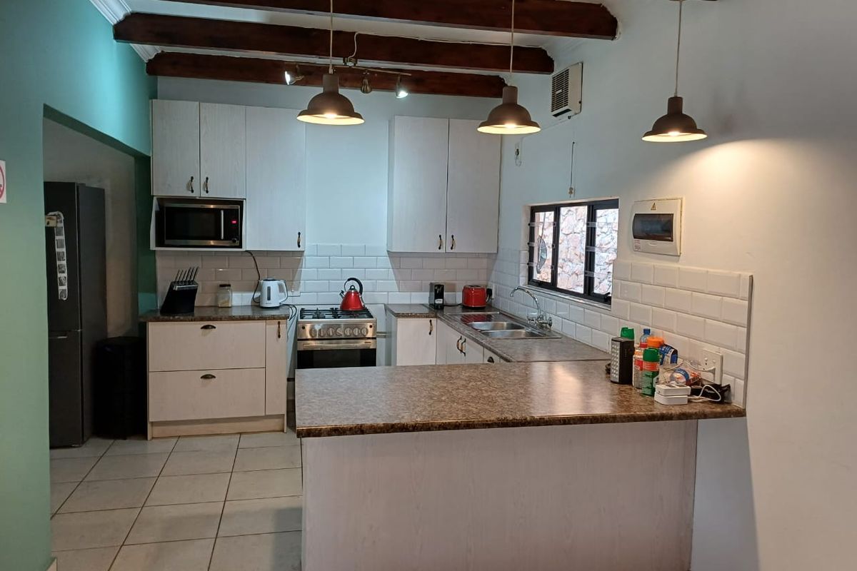 A functional kitchen featuring exposed timber ceiling beams, subway tile backsplash, laminate countertops, and a gas hob with built-in oven.