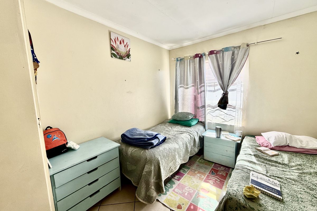 A functional bedroom featuring tiled flooring and a window with curtain fixtures, providing a practical space for sleeping or study.