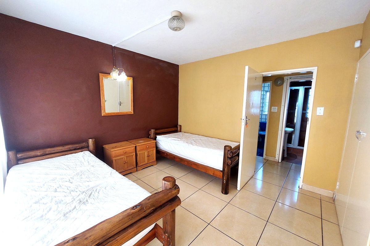 A bedroom featuring tiled flooring, built-in storage, and direct access to an en-suite bathroom.