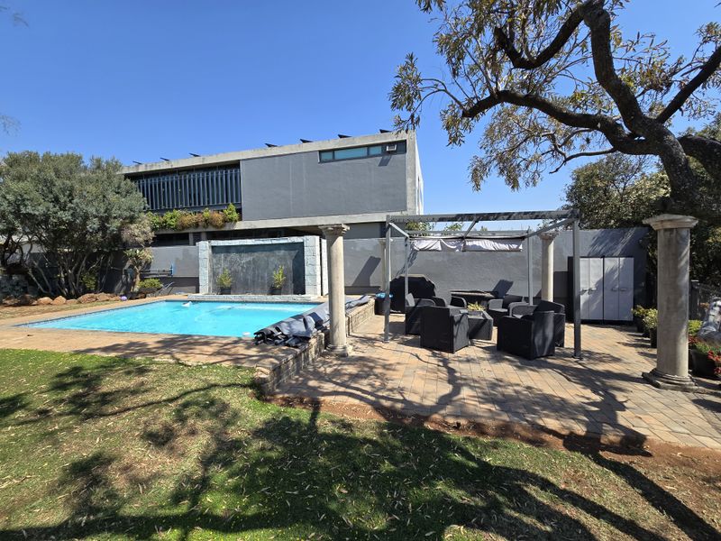 Outdoor pool area featuring a swimming pool, water feature, and a paved patio with a pergola structure.