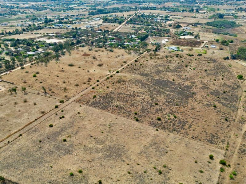 An aerial view of a large, undeveloped residential land parcel featuring natural vegetation and dirt access tracks in a rural setting.