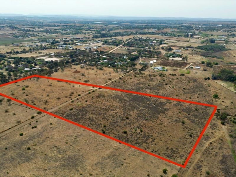 An aerial view of a large, undeveloped residential plot of land with clear boundary markings, situated in a rural or semi-rural landscape.
