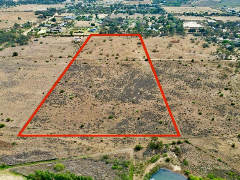 An aerial view of a large, undeveloped residential vacant land plot with clear boundary markings, situated in a rural or semi-rural landscape.