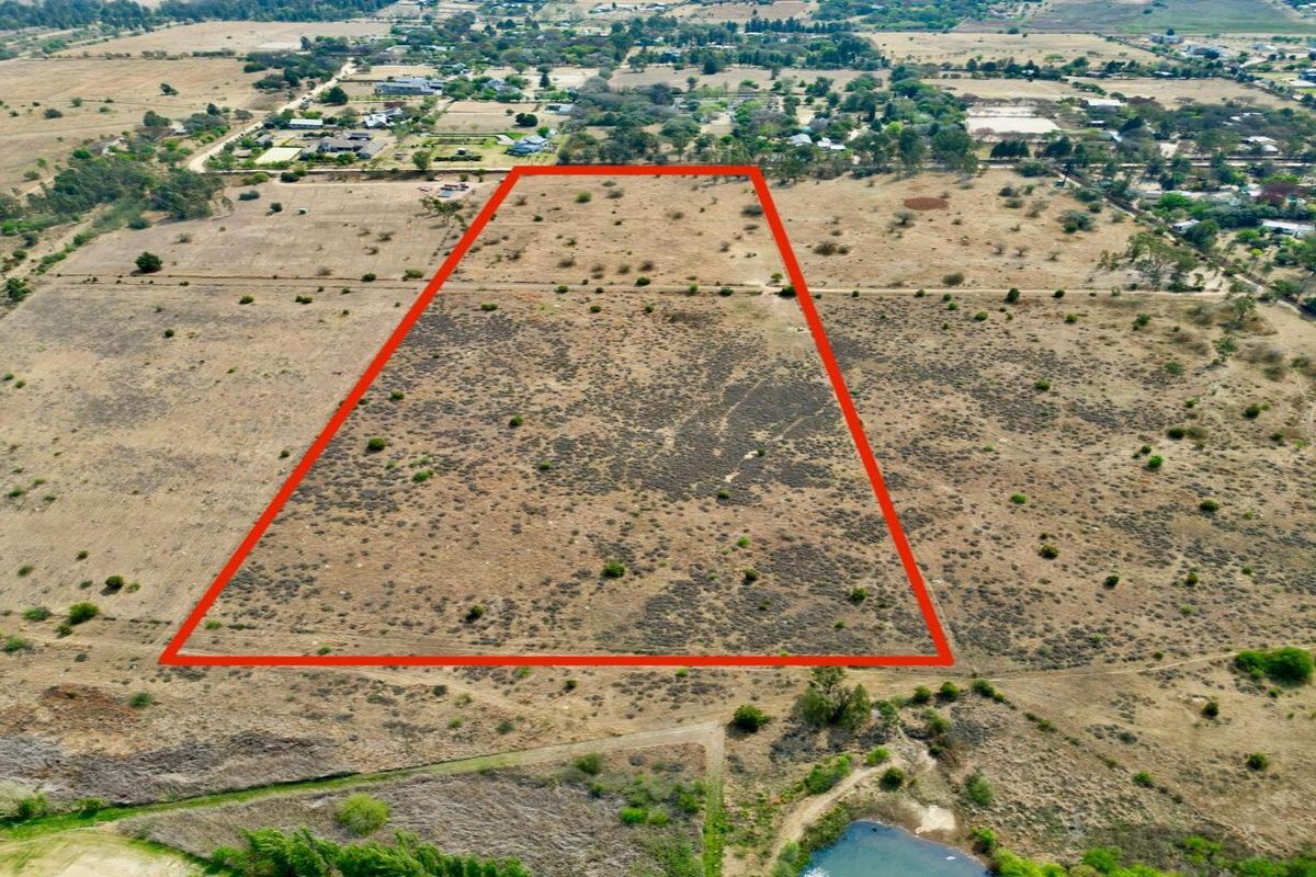 An aerial view of a large, undeveloped residential vacant land plot with clear boundary markings, situated in a rural or semi-rural landscape.