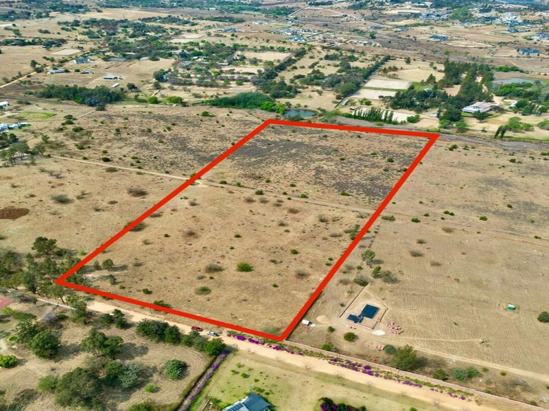 An aerial view of a large, vacant residential plot of land with clear boundary markings, situated in a rural or semi-rural estate setting.
