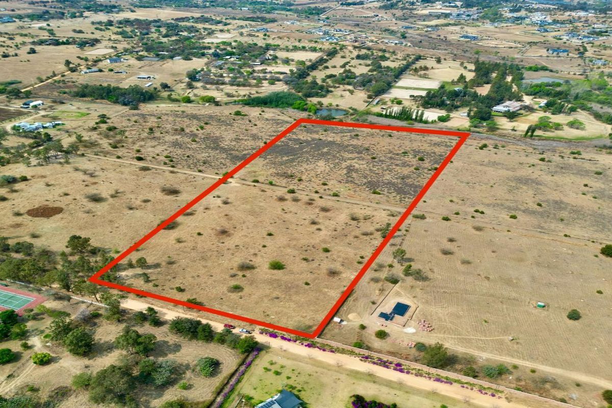 An aerial view of a large, vacant residential plot of land with clear boundary markings, situated in a rural or semi-rural estate setting.