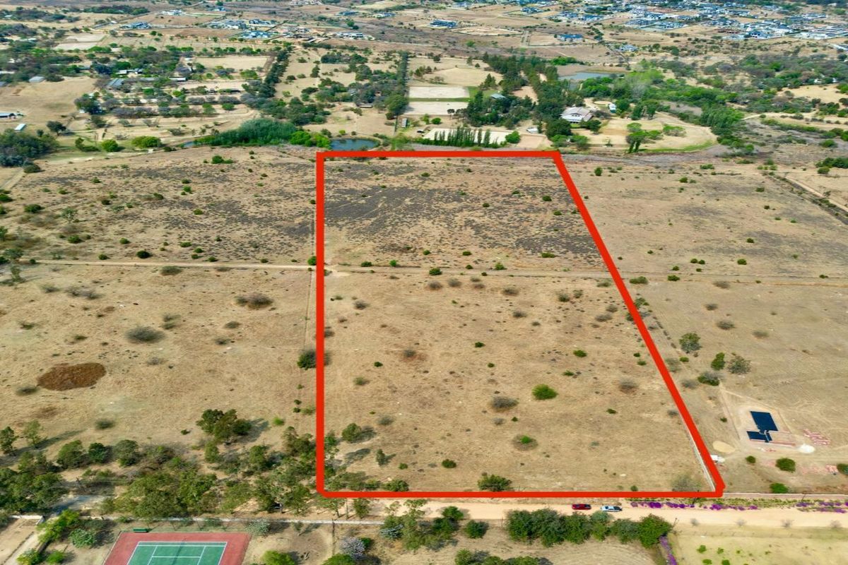 An aerial view of a large, vacant residential plot with clear boundary markings, situated in a semi-rural estate setting.