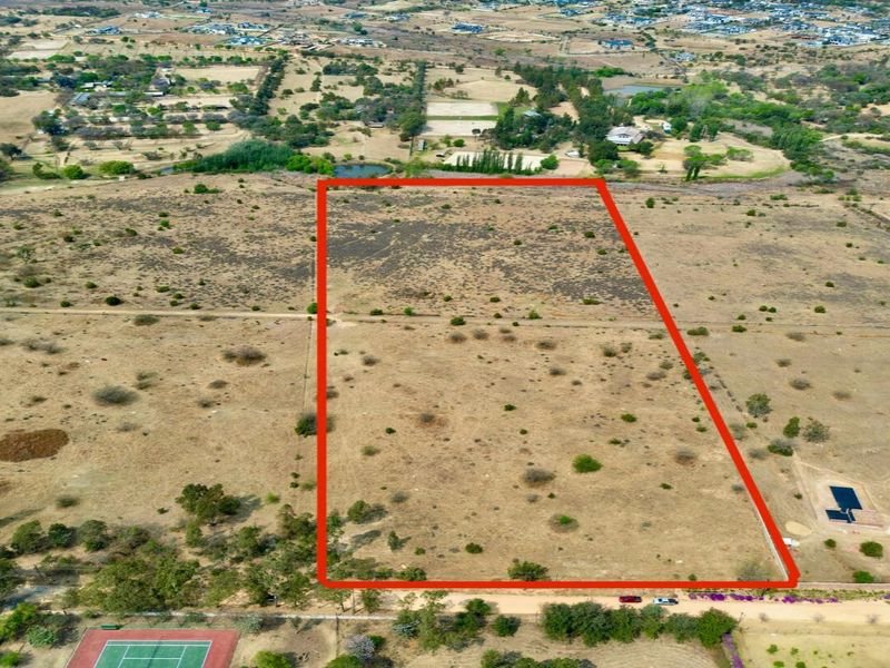 An aerial view of a large, vacant residential plot with clear boundary markings, situated in a semi-rural estate setting.
