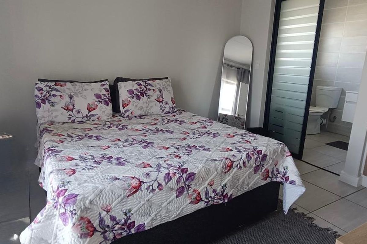 A well-maintained bedroom featuring built-in cupboards, tiled flooring, and direct access to an en-suite bathroom.