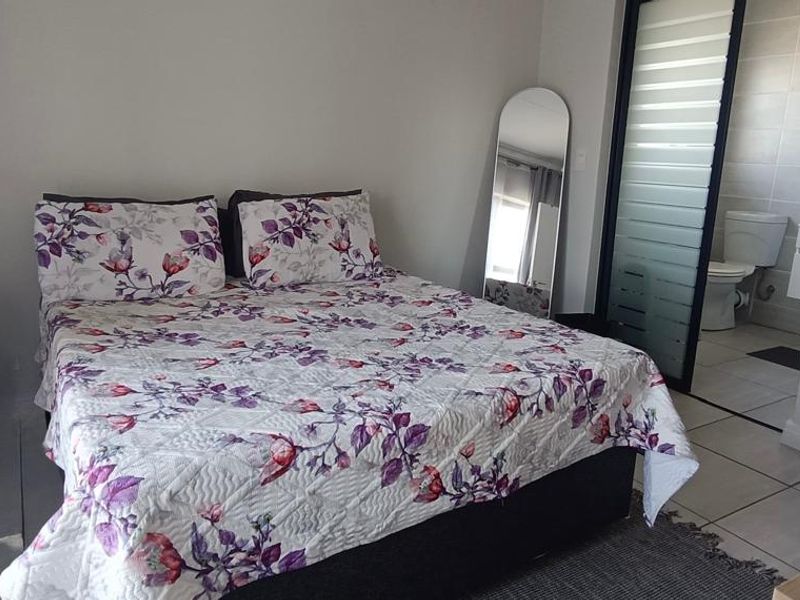 A well-maintained bedroom featuring built-in cupboards, tiled flooring, and direct access to an en-suite bathroom.
