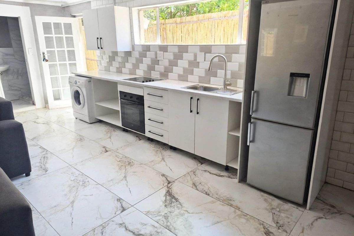Modern kitchen featuring white cabinetry, subway tile backsplash, marble-look floor tiles, and integrated appliances, offering a clean and functional cooking space.