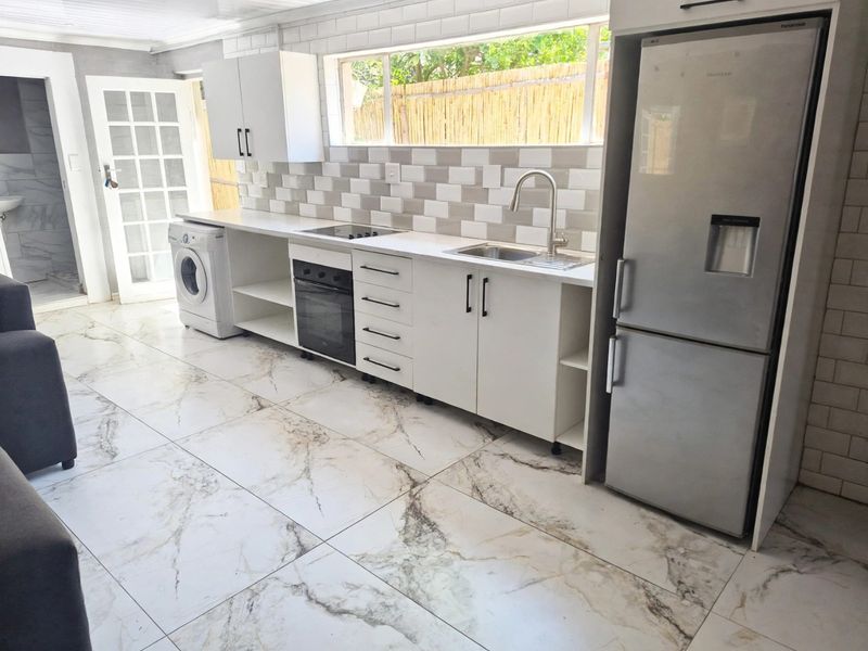 Modern kitchen featuring white cabinetry, subway tile backsplash, marble-look floor tiles, and integrated appliances, offering a clean and functional cooking space.
