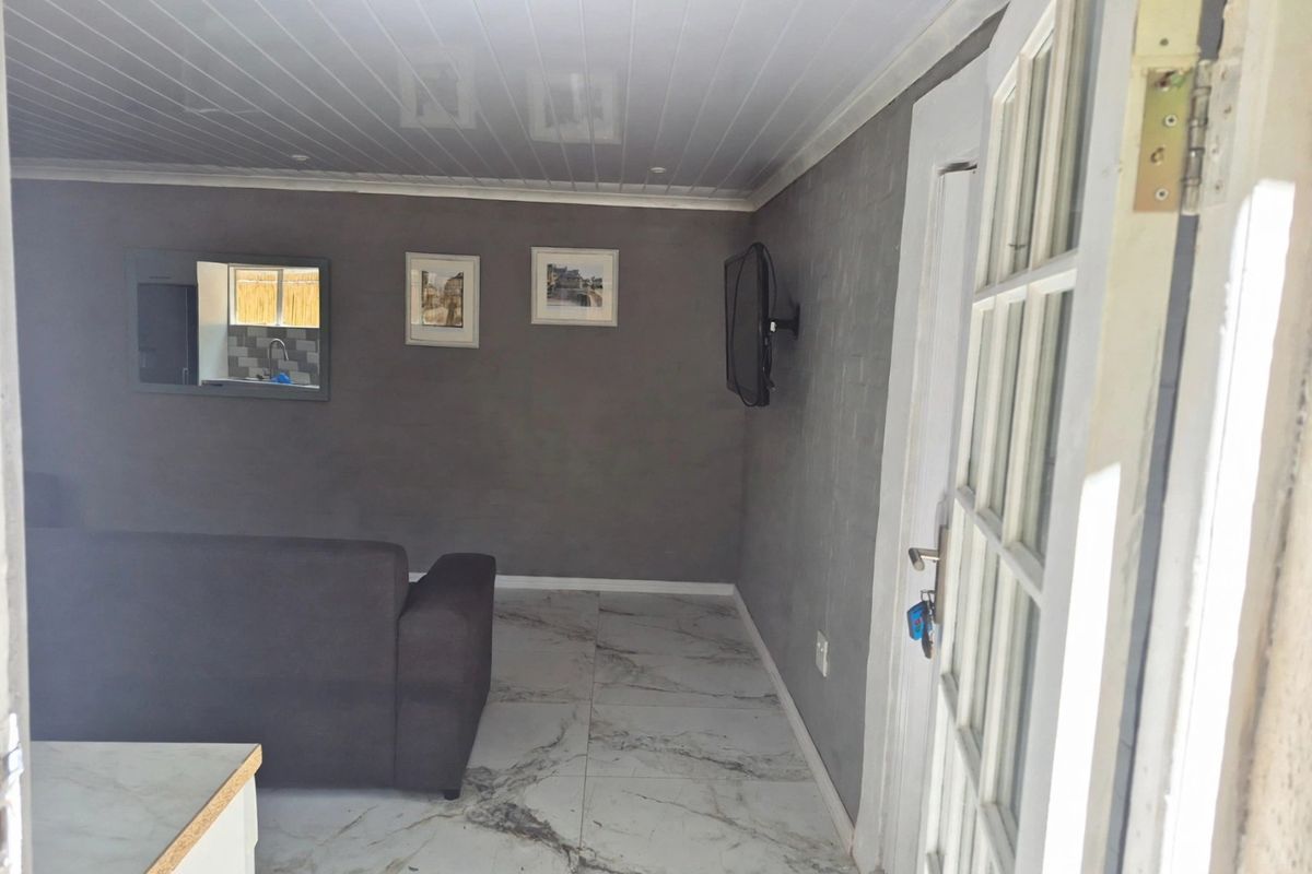 A living room featuring marble-look floor tiles, a tongue and groove ceiling, and a convenient pass-through window connecting to the kitchen area.
