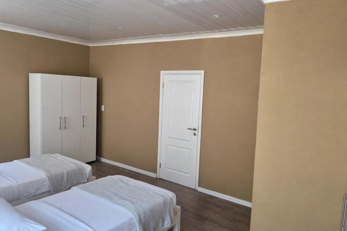 A well-maintained bedroom featuring laminate flooring, a tongue and groove ceiling with recessed lighting, and a built-in wardrobe.