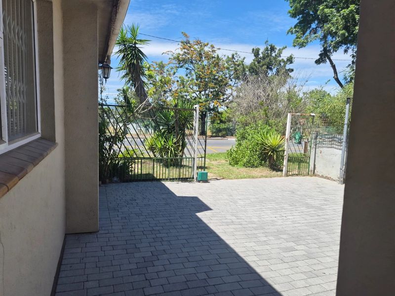 A paved front entrance area featuring a metal security gate and exterior wall lighting, providing direct access to the property from the street.