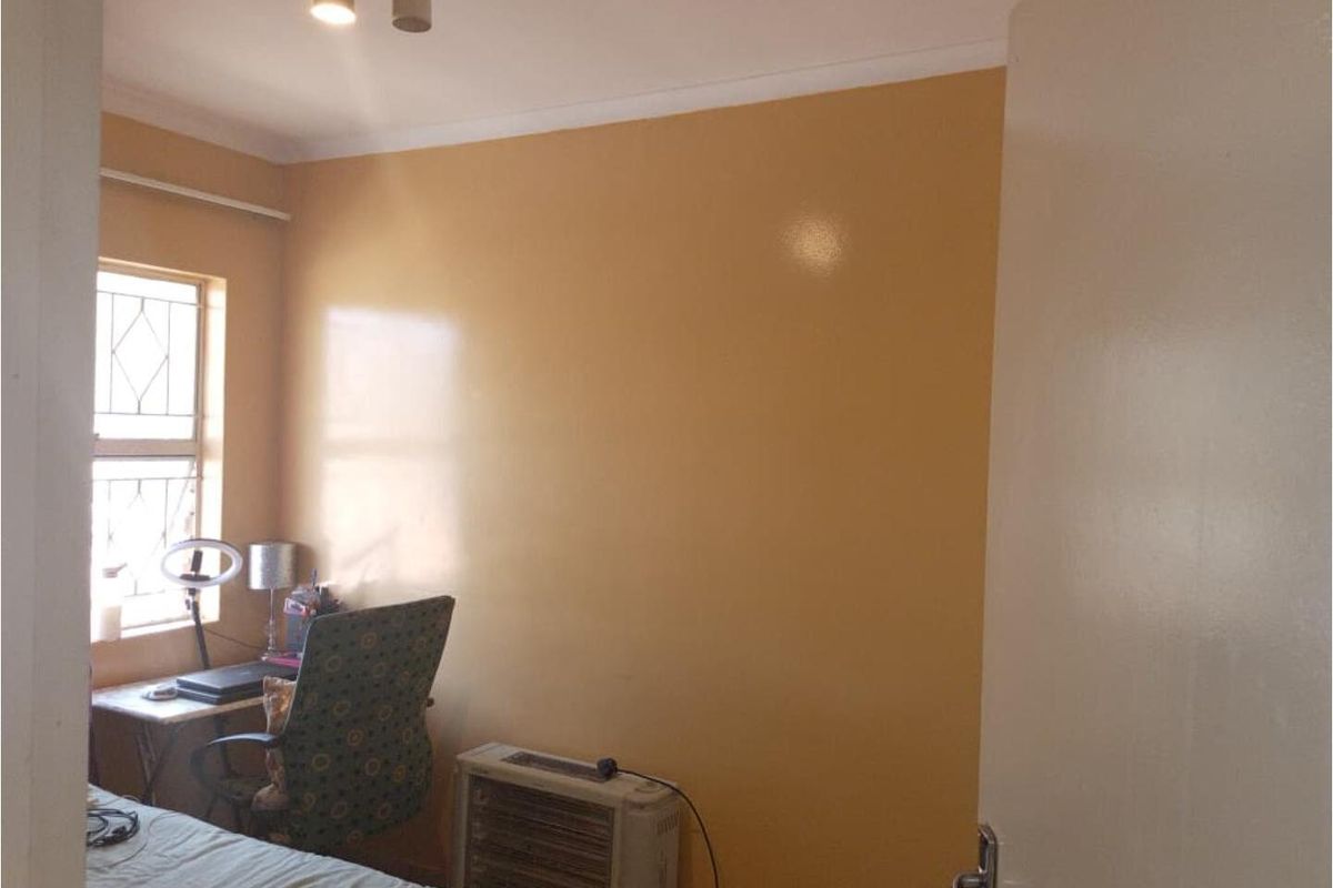 A bedroom featuring a window with security bars, neutral wall paint, and ceiling-mounted lighting.