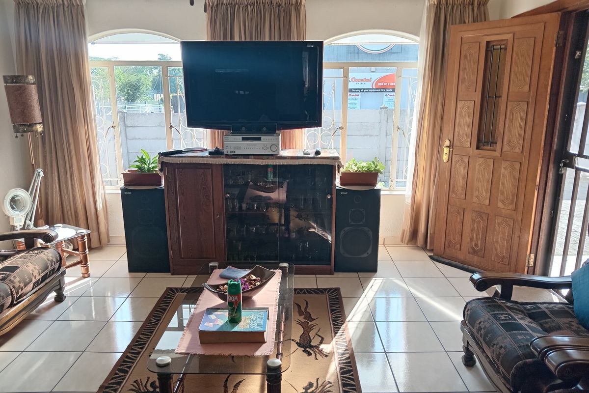 A living room featuring tiled flooring, arched windows, and a solid timber entrance door, providing a functional and traditional living space.