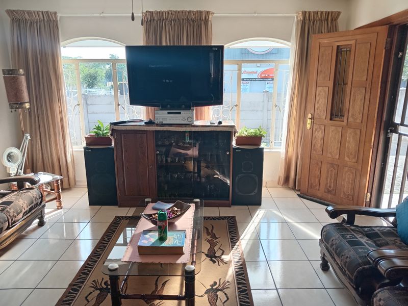 A living room featuring tiled flooring, arched windows, and a solid timber entrance door, providing a functional and traditional living space.