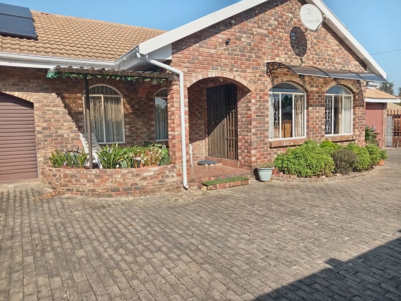 Front elevation of a face brick townhouse featuring a paved driveway, arched entrance, security features, and integrated solar water heating system.