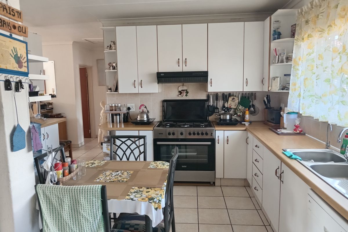 Functional kitchen featuring white cabinetry, gas stove with oven, extractor fan, double basin sink, and tiled flooring.