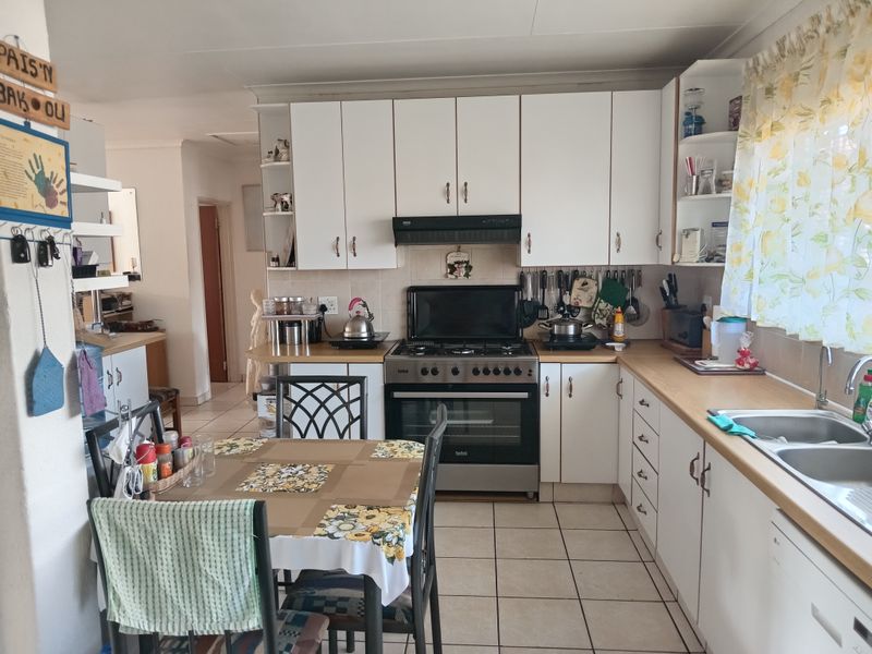 Functional kitchen featuring white cabinetry, gas stove with oven, extractor fan, double basin sink, and tiled flooring.