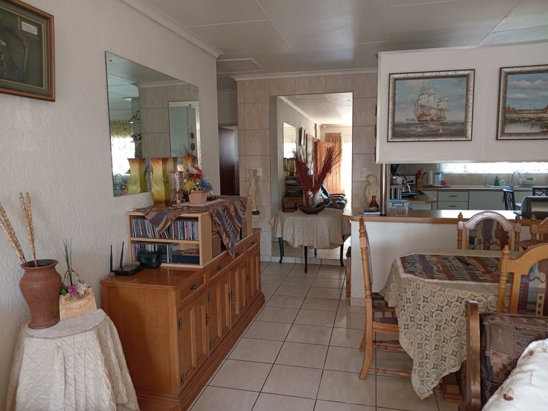 Open-plan living and dining area featuring tiled flooring, a breakfast bar, and a view into the adjacent kitchen space.
