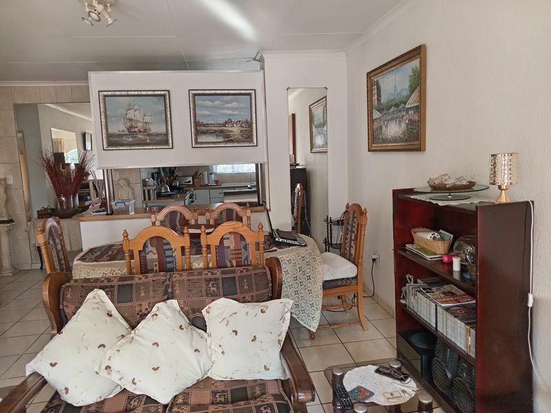 Open plan living and dining area featuring ceramic floor tiles and a convenient pass-through window connecting to the kitchen space.