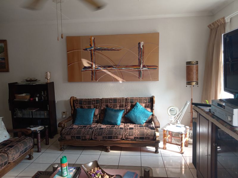 A living room featuring ceramic floor tiles and a ceiling fan, providing a functional space with neutral wall finishes.