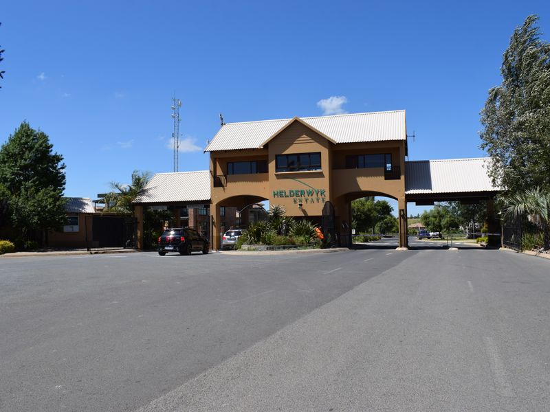 The main entrance gatehouse of Helderwyk Estate, featuring a secure access point, paved driveway, and established landscaping.