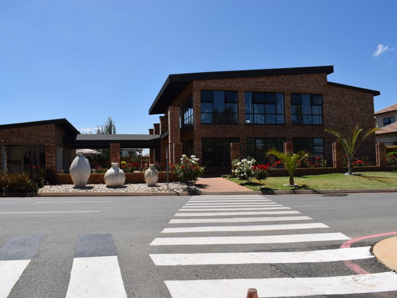 Front view of a modern brick residential building featuring large windows, a paved entrance path, and well-maintained landscaped garden areas.