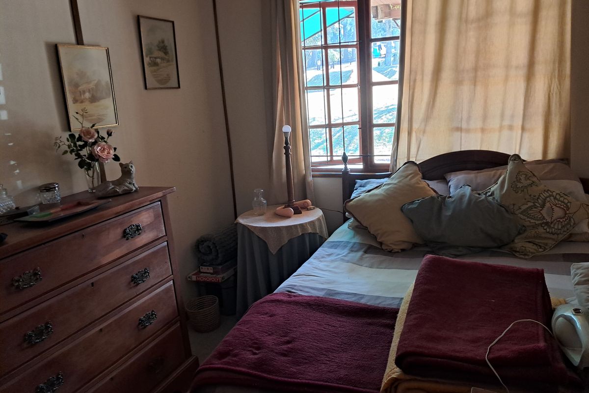 A cozy bedroom featuring a wooden window frame and traditional finishes, offering a comfortable and lived-in atmosphere.