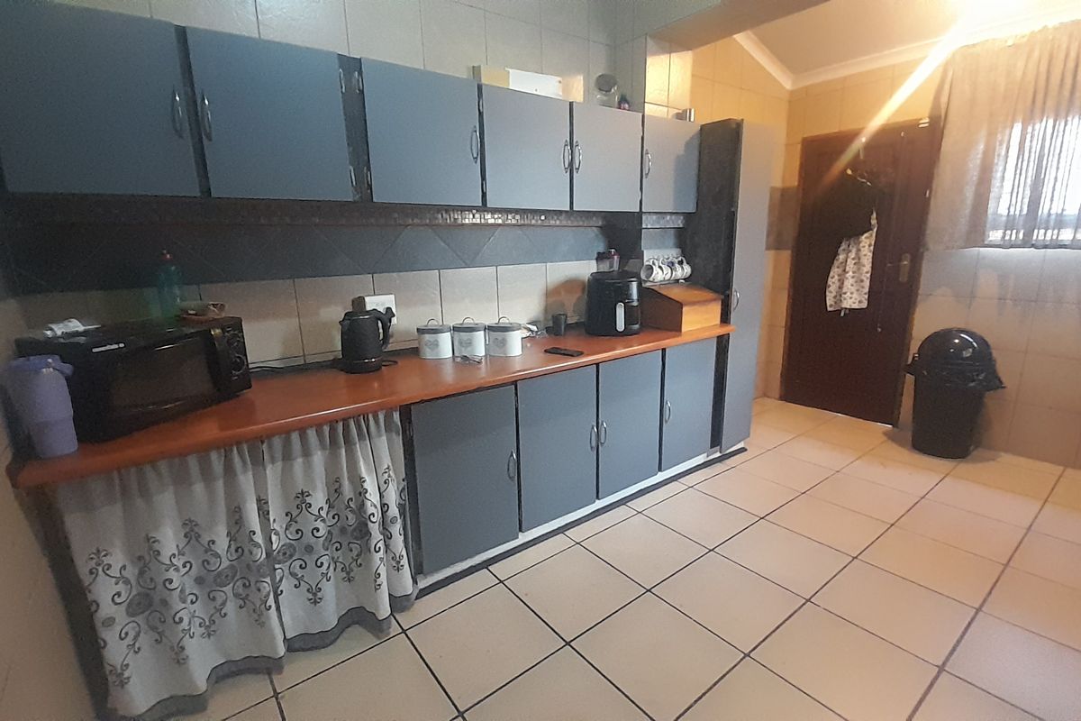 A functional kitchen featuring tiled flooring, a tiled backsplash, and built-in cabinetry with a laminate countertop.