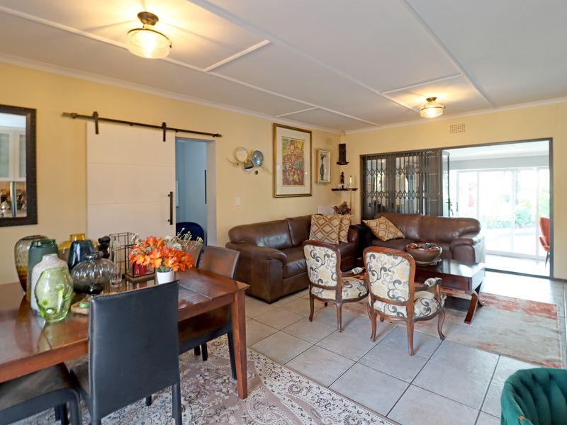 Spacious open-plan living and dining area featuring tiled flooring, a sliding barn door, and direct access to an outdoor patio through a security gate.