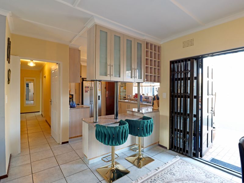 A functional kitchen featuring granite countertops, built-in cabinetry with a wine rack, and a breakfast bar, with direct access to an outdoor area.