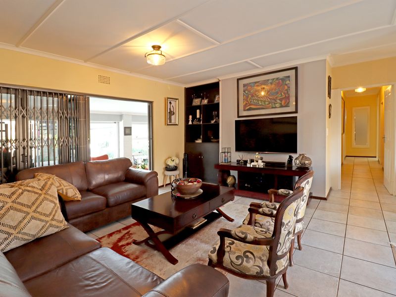 A comfortable living room featuring tiled floors, built-in shelving, and direct access to an outdoor patio area through sliding security gates.