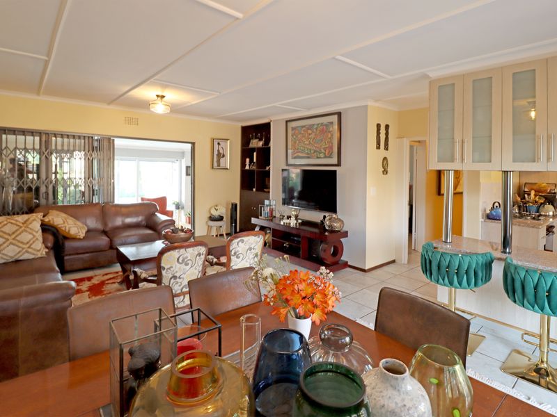 Spacious open-plan living and dining area featuring tiled floors, a breakfast bar with built-in cabinetry, and direct access to an outdoor patio space.
