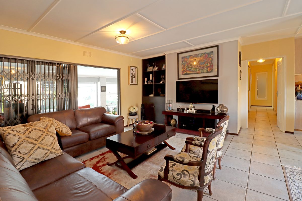 A comfortable living room featuring tiled floors, built-in shelving, and direct access to an outdoor patio area through sliding security gates.