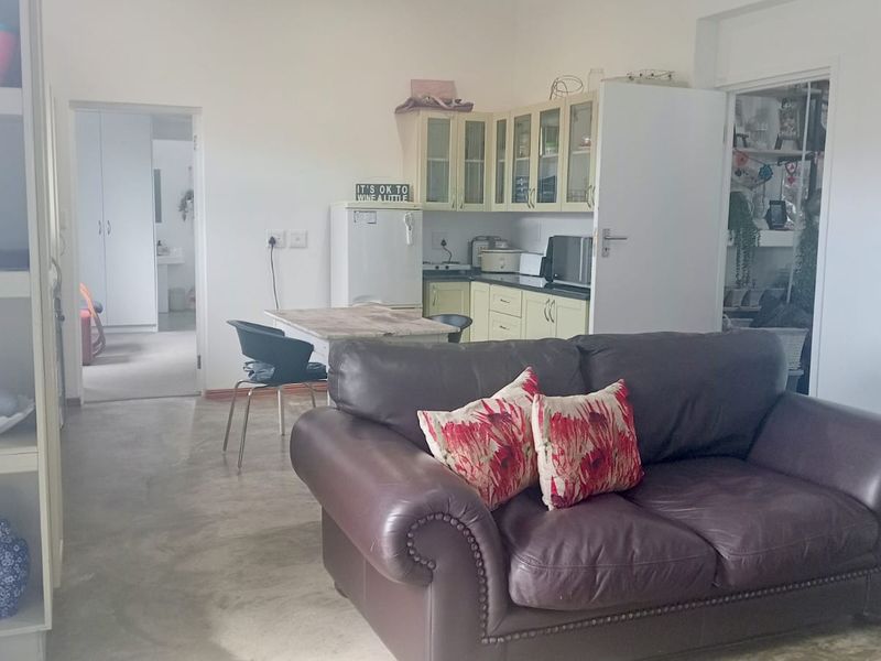 Open plan living area featuring concrete flooring and a compact kitchen with built-in cabinetry and countertops.