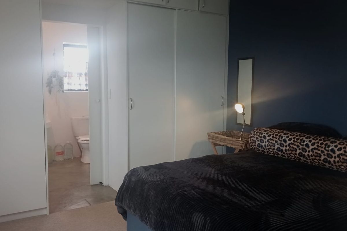 Bedroom featuring built-in cupboards and an adjoining en-suite bathroom with a toilet.
