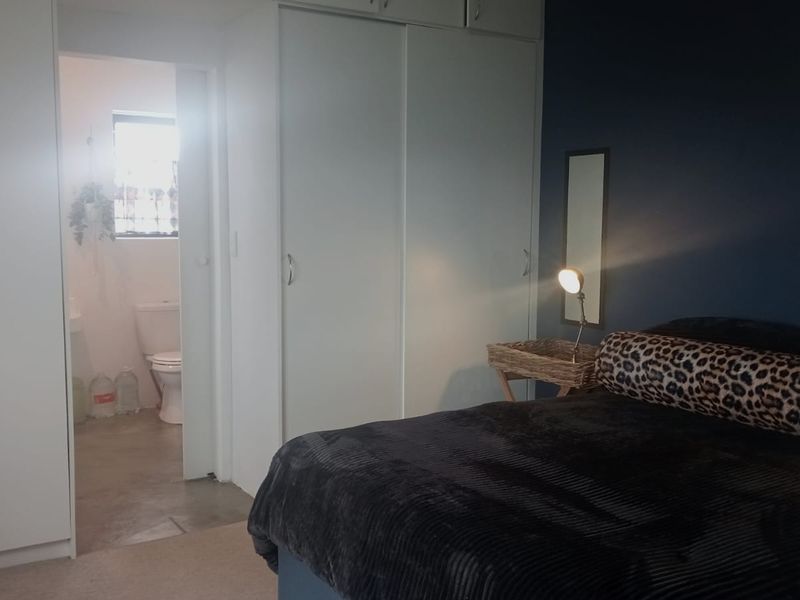 Bedroom featuring built-in cupboards and an adjoining en-suite bathroom with a toilet.