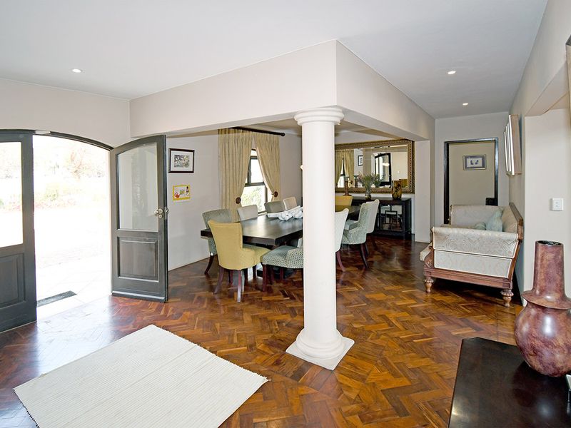 Open plan living and dining area featuring classic parquet flooring, a central structural column, and an arched entrance door leading to the exterior.