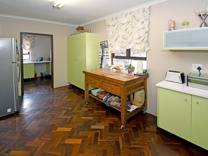 Kitchen featuring classic herringbone parquet flooring, built-in cabinetry, and a functional layout with an adjacent scullery area.