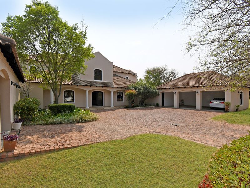 Spacious front exterior featuring a large brick-paved driveway, a triple garage, and a well-maintained garden leading to the main entrance.