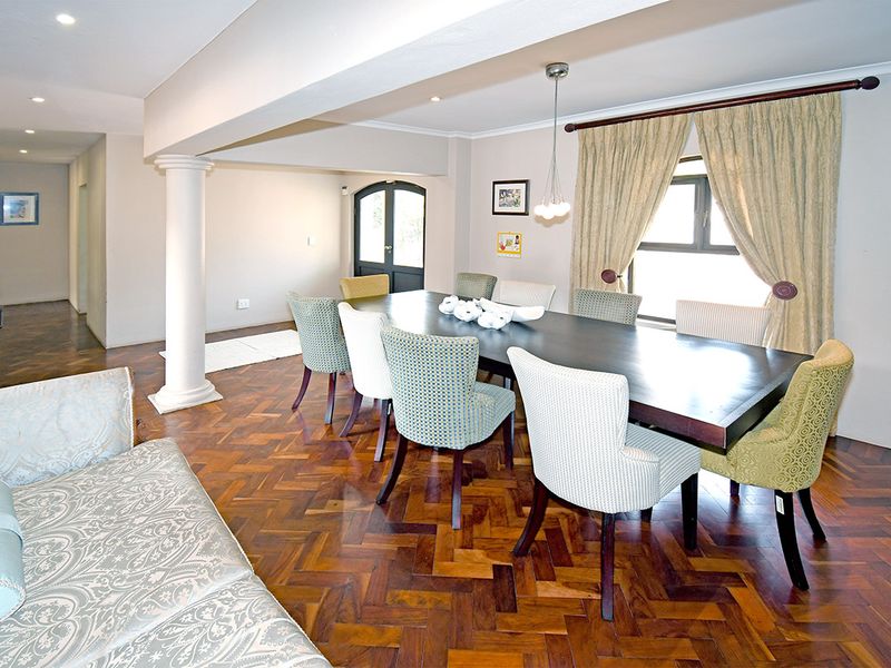 Spacious dining area featuring classic herringbone parquet flooring, a decorative structural column, and recessed lighting, creating a warm and inviting atmosphere.