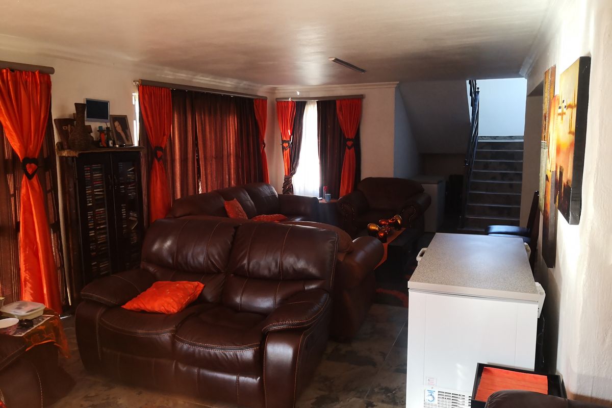 A spacious living room area featuring tiled flooring and an internal staircase leading to the upper level.
