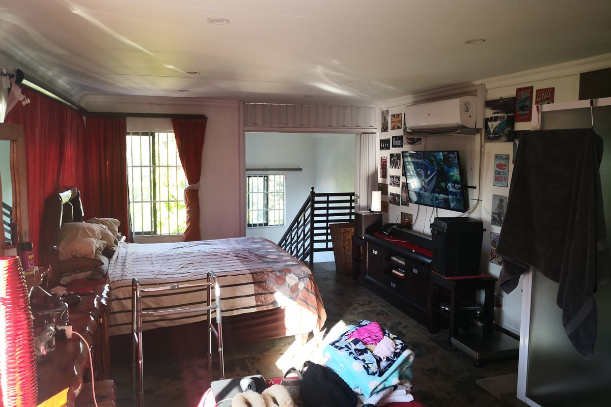 Spacious bedroom featuring recessed lighting, split-system air conditioning, and direct access to an internal staircase with safety railing.