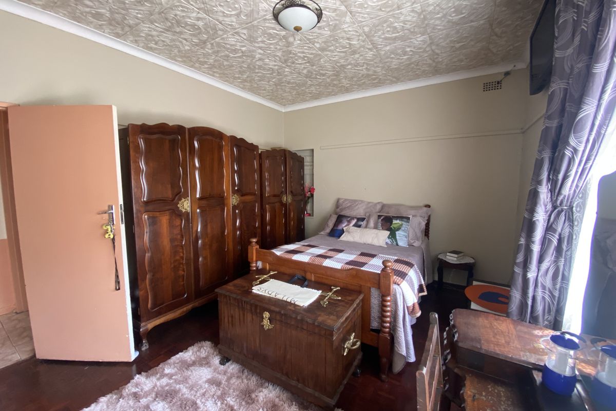 A bedroom featuring a decorative pressed metal ceiling, hardwood flooring, and a large built-in wooden wardrobe.