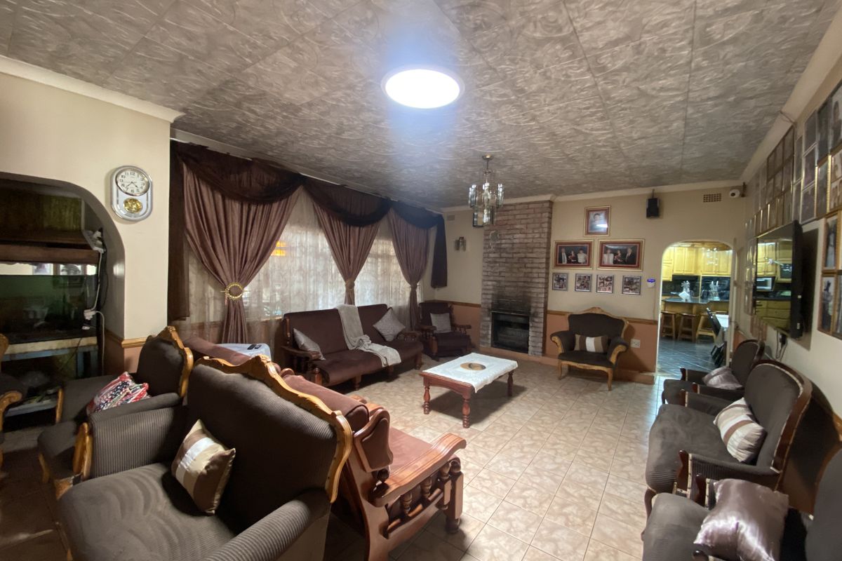 Spacious living room featuring a brick fireplace, tiled flooring, and a textured ceiling, with an open archway leading to the kitchen area.