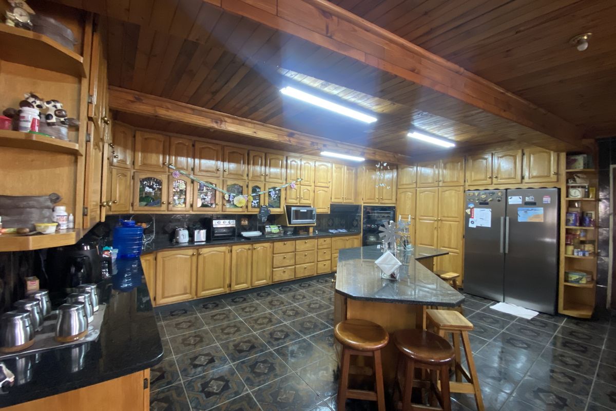 Spacious kitchen featuring extensive timber cabinetry, granite countertops, a central island, and a distinctive timber-paneled ceiling with integrated lighting.